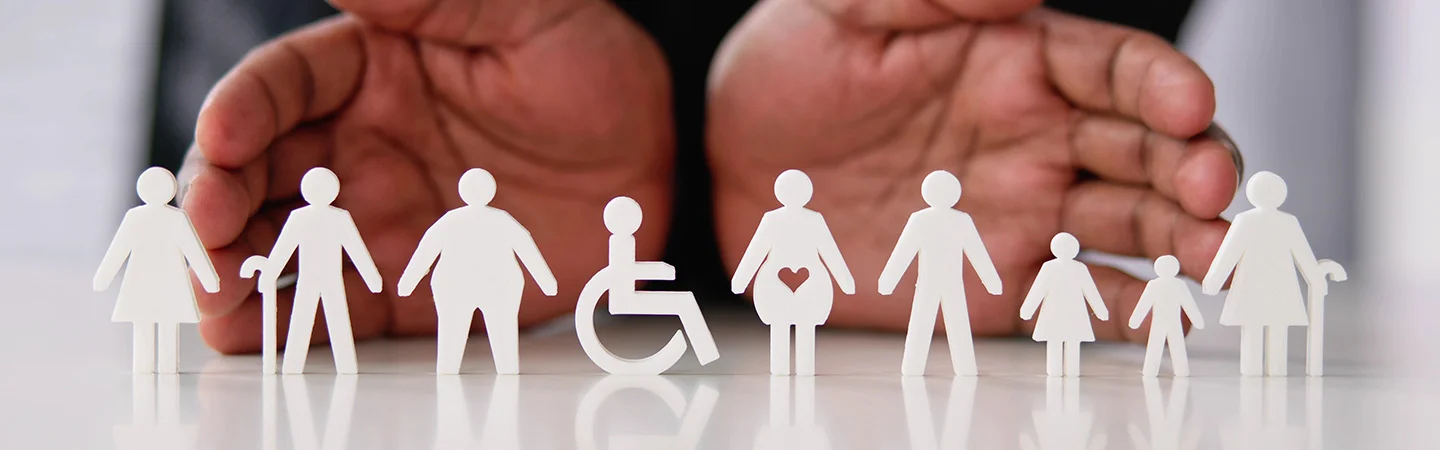 Hands displaying diverse and differently-abled paper figures representing inclusion and belonging
