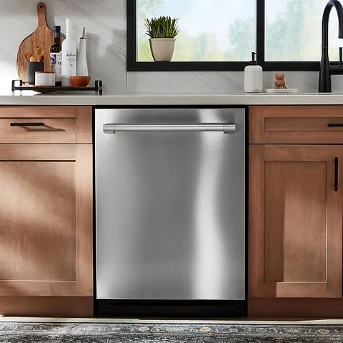 Built-in stainless steel dishwasher located in kitchen with brown cabinets on each side