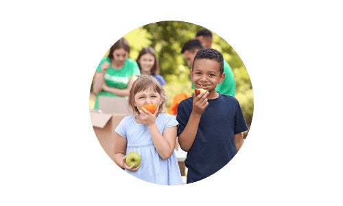 Boy and girl eating apples at community donation event