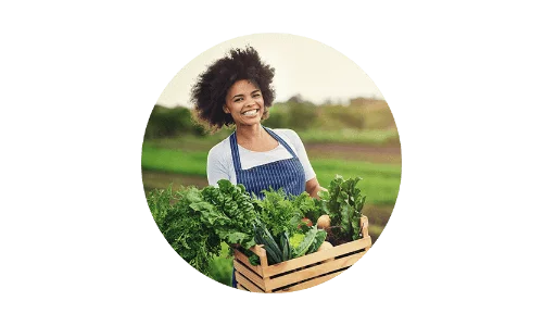 Woman carrying carton of produce in green field