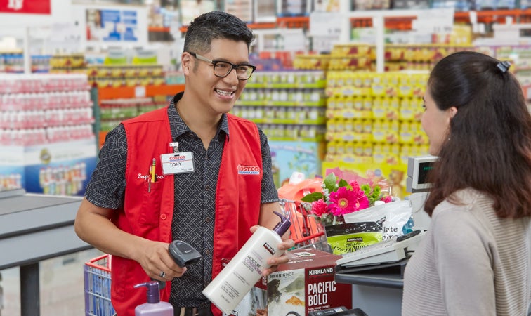 Costco employee at register helping Costco member to check out