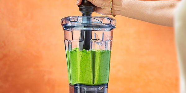 blender with green liquid, possibly a healthy smoothie or juice, ready to be mixed.