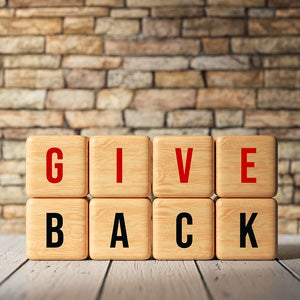Wooden blocks spelling out "Give Back" on table