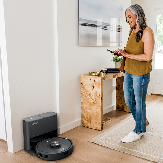 Woman using mobile device next to a robot vacuum