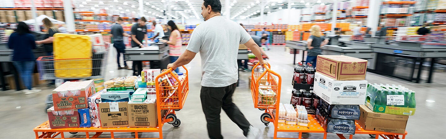 Costco member pushing two carts packed with great finds at a Costco warehouse