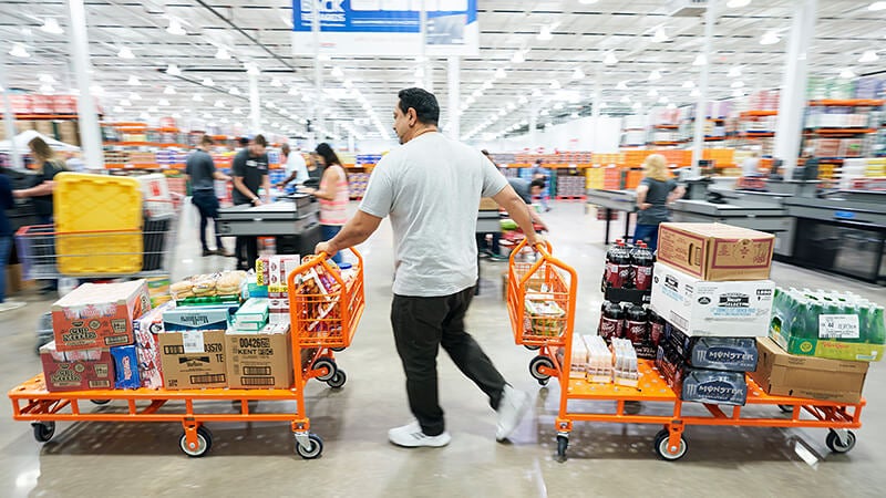 Costco member pushing two carts packed with great finds at a Costco warehouse