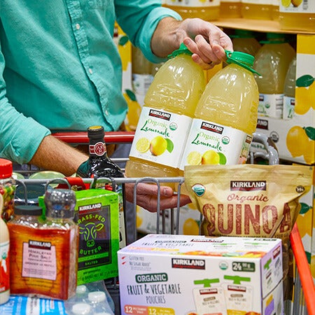 Costco member placing Kirkland Signature items in Costco shopping cart